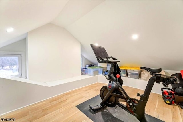 workout room featuring vaulted ceiling and wood finished floors