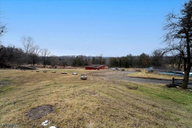 view of yard with an outbuilding, a rural view, and a forest view