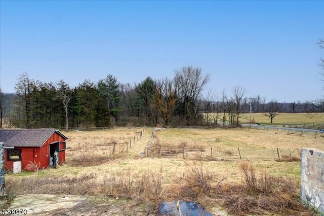 view of yard featuring a rural view, fence, and an outdoor structure