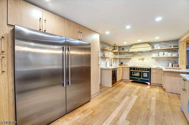 kitchen featuring open shelves, light countertops, custom range hood, light brown cabinetry, and high quality appliances