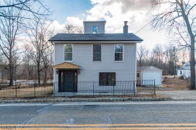 view of front of property with an outbuilding, a fenced front yard, a garage, driveway, and a chimney