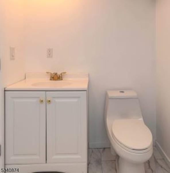 bathroom with marble finish floor, baseboards, vanity, and toilet