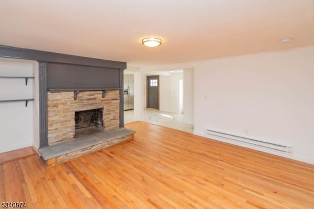 unfurnished living room with light wood finished floors, a stone fireplace, and baseboard heating