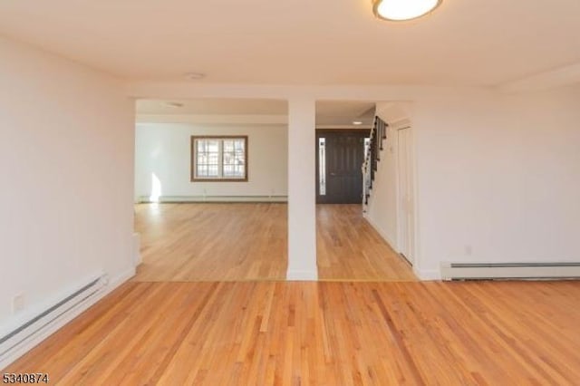 unfurnished room featuring a baseboard heating unit, light wood finished floors, and a baseboard radiator