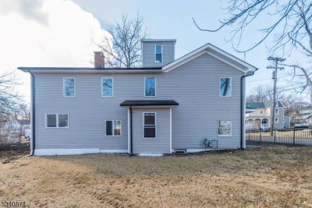 rear view of house featuring fence and a lawn