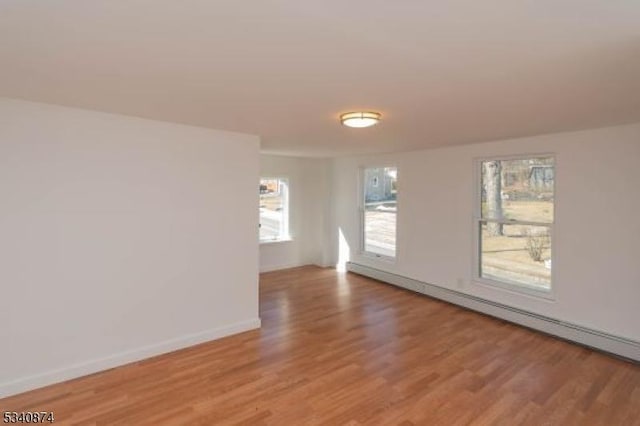 empty room with light wood-style floors, a baseboard radiator, and baseboards