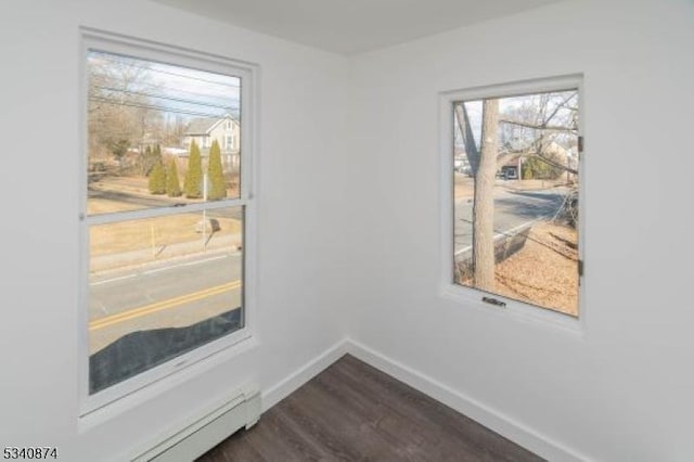 spare room featuring dark wood-style floors and baseboards