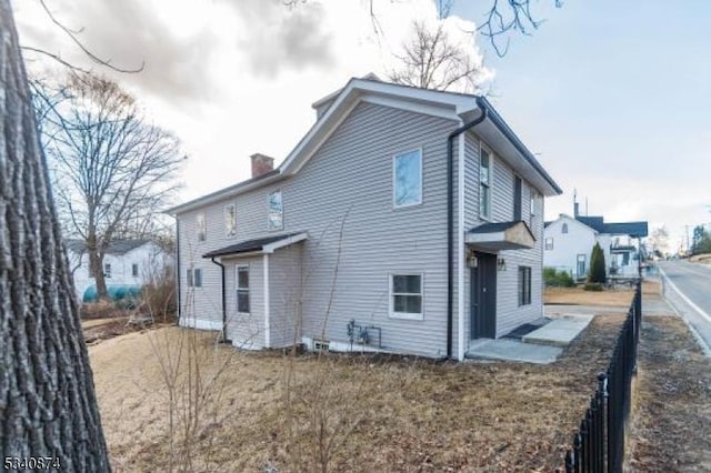 back of property with a chimney and fence