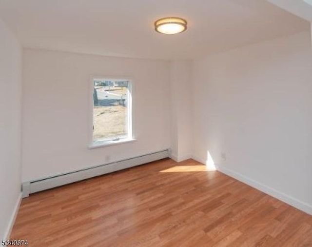 unfurnished room featuring light wood finished floors, baseboards, and a baseboard heating unit