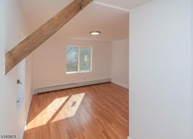 additional living space featuring a baseboard heating unit, beamed ceiling, and wood finished floors