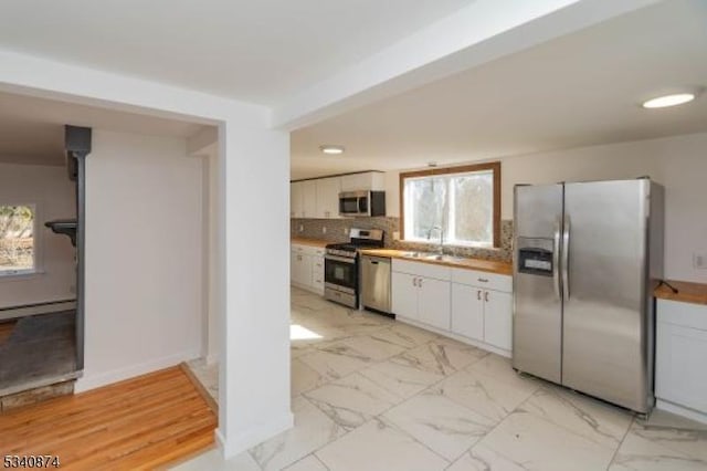 kitchen featuring marble finish floor, appliances with stainless steel finishes, backsplash, and white cabinetry