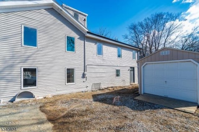 view of side of property with driveway, an outdoor structure, and a detached garage