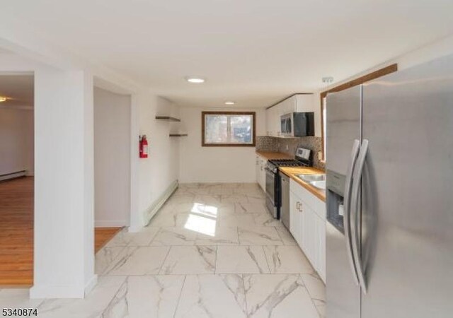 kitchen with marble finish floor, appliances with stainless steel finishes, white cabinetry, and tasteful backsplash