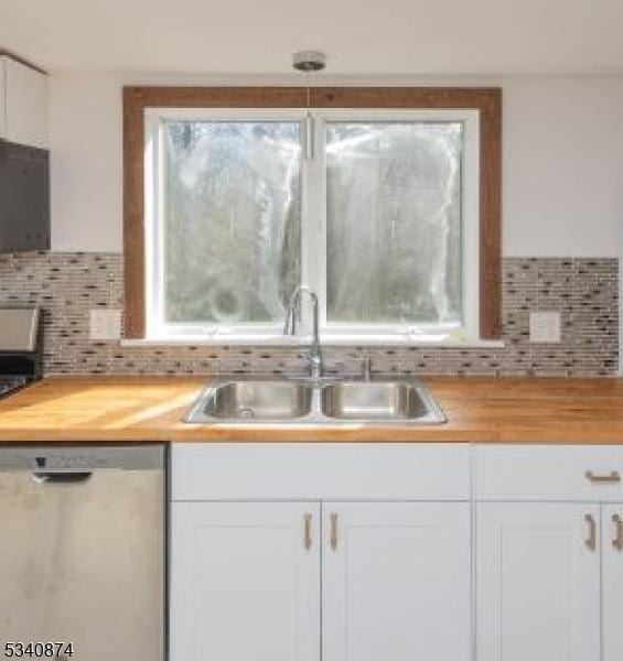 kitchen featuring wooden counters, stainless steel dishwasher, a sink, and a healthy amount of sunlight