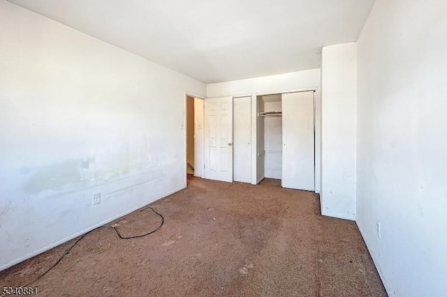 unfurnished bedroom with multiple closets and carpet flooring