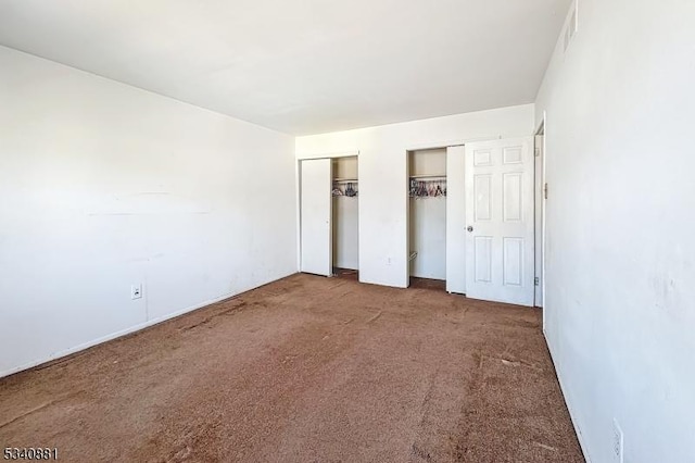 unfurnished bedroom with carpet and two closets