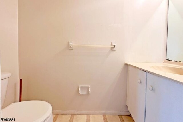 bathroom featuring vanity, toilet, and baseboards