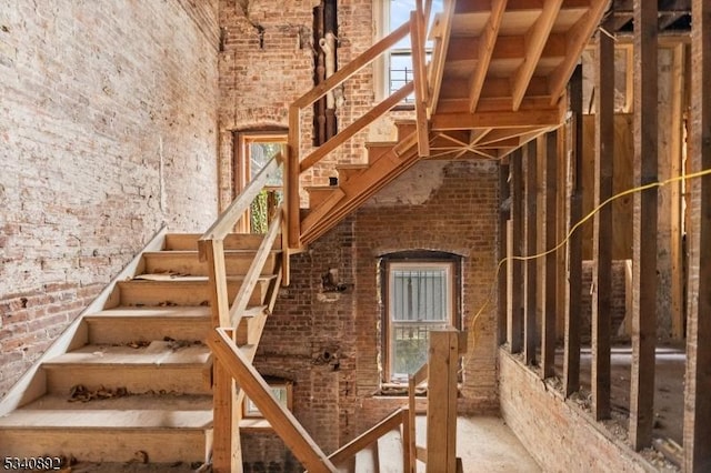 stairs featuring brick wall and a high ceiling