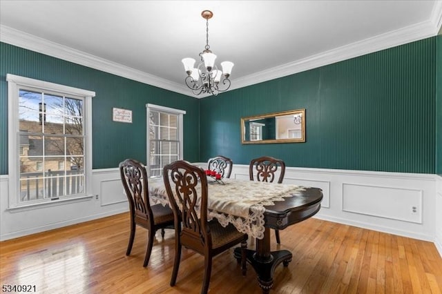 dining room featuring ornamental molding, hardwood / wood-style flooring, and an inviting chandelier