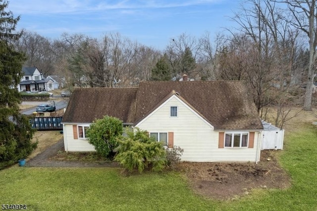 back of property featuring a shingled roof and a lawn