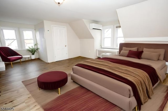 bedroom featuring wood finished floors, a wall mounted air conditioner, and multiple windows