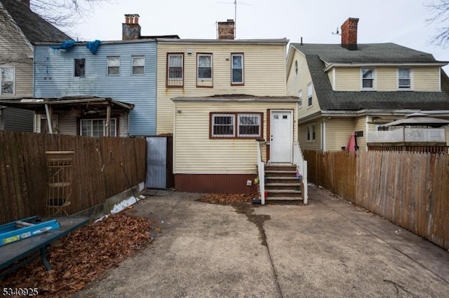 rear view of property with entry steps and fence