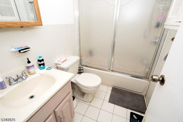 full bathroom with tile walls, toilet, combined bath / shower with glass door, vanity, and tile patterned flooring