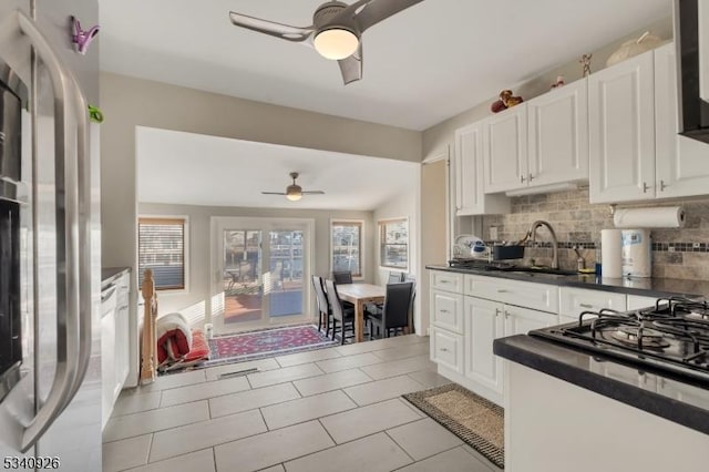 kitchen with dark countertops, ceiling fan, stainless steel refrigerator, and decorative backsplash