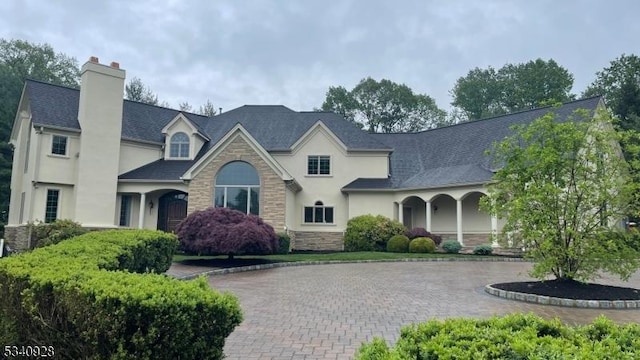 35 Geiger Ln, Warren Twp, NJ 07059 - view of front of home featuring stone siding, stucco siding, a chimney, and curved driveway