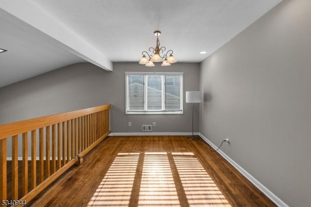 spare room featuring visible vents, baseboards, wood finished floors, beamed ceiling, and a chandelier