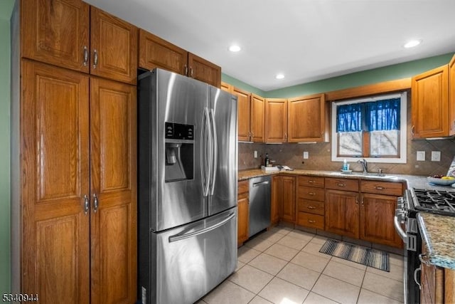 kitchen with light tile patterned floors, appliances with stainless steel finishes, brown cabinets, and a sink