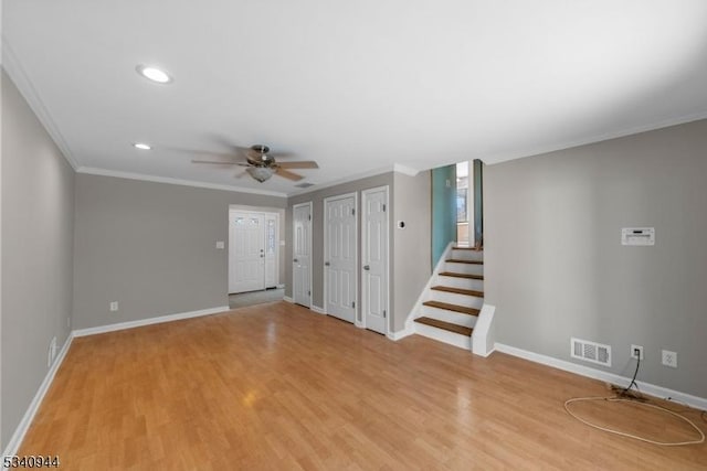 unfurnished living room featuring visible vents, baseboards, stairs, ornamental molding, and light wood finished floors