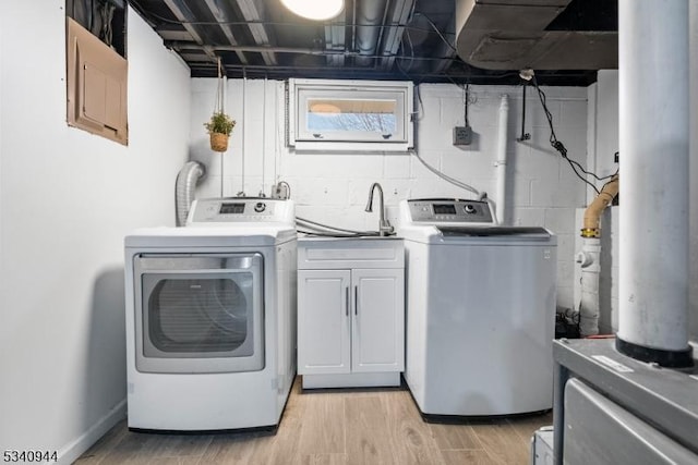 laundry room with washer and dryer, cabinet space, a sink, and light wood-style flooring