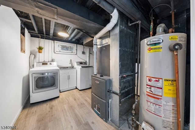 clothes washing area with laundry area, baseboards, water heater, washer and dryer, and light wood-type flooring