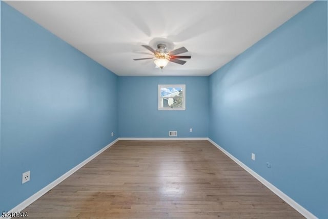 unfurnished room featuring a ceiling fan, visible vents, baseboards, and wood finished floors