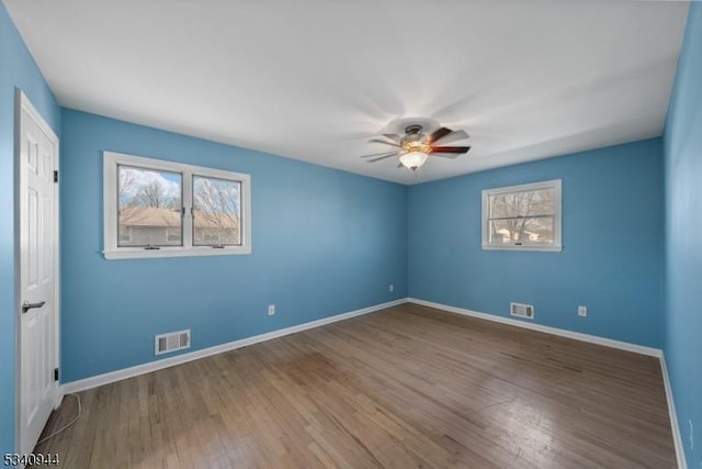 unfurnished room with a ceiling fan, baseboards, visible vents, and wood finished floors