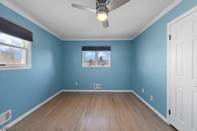 unfurnished bedroom featuring wood finished floors, visible vents, baseboards, and multiple windows