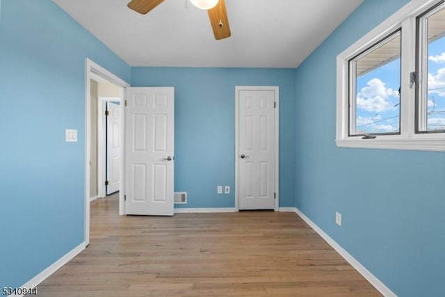 unfurnished bedroom with light wood-style floors, visible vents, baseboards, and a ceiling fan