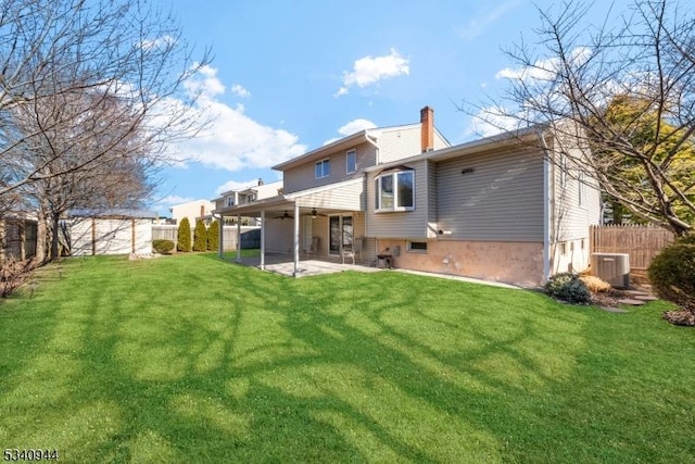 rear view of property featuring a patio area, ceiling fan, a chimney, and a fenced backyard