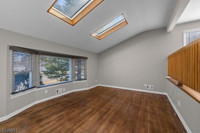 unfurnished room with vaulted ceiling with skylight, wood finished floors, visible vents, and baseboards