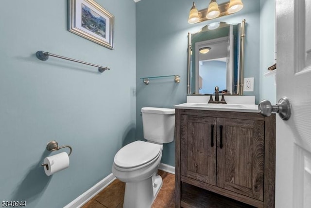 half bathroom featuring tile patterned flooring, baseboards, vanity, and toilet