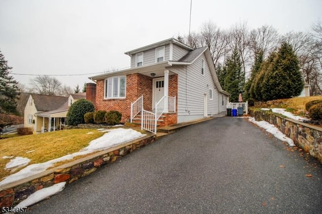 view of front of house featuring aphalt driveway, a front lawn, and brick siding