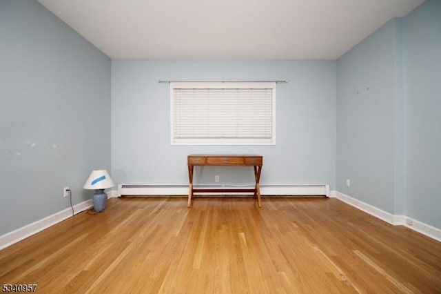 unfurnished room with a baseboard radiator, baseboards, and wood finished floors