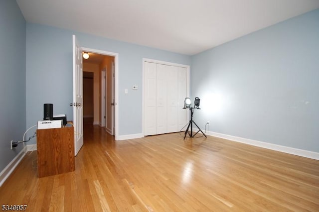 unfurnished bedroom with light wood finished floors, baseboards, and a closet