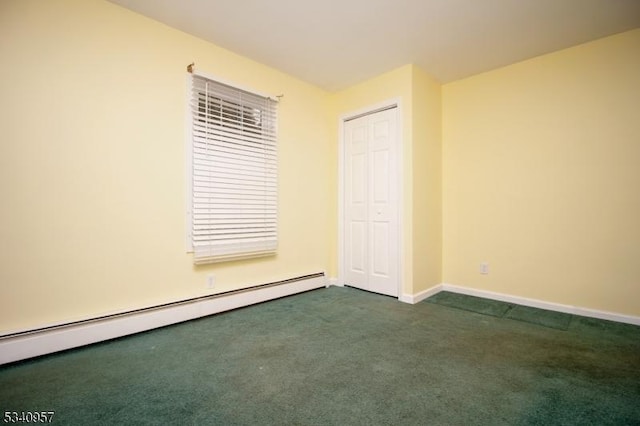 spare room with a baseboard radiator, dark carpet, and baseboards