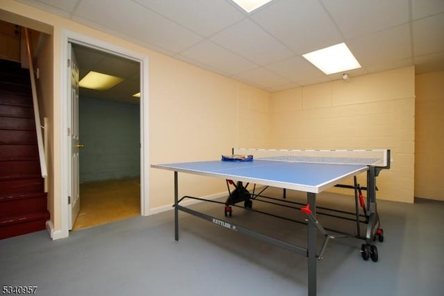 rec room featuring a paneled ceiling, concrete flooring, and concrete block wall