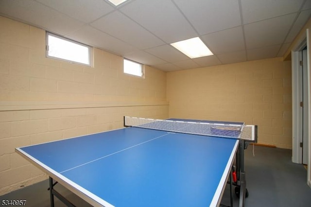 playroom featuring concrete block wall and a drop ceiling