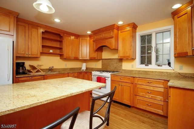 kitchen with light stone counters, light wood-style flooring, white appliances, a sink, and open shelves