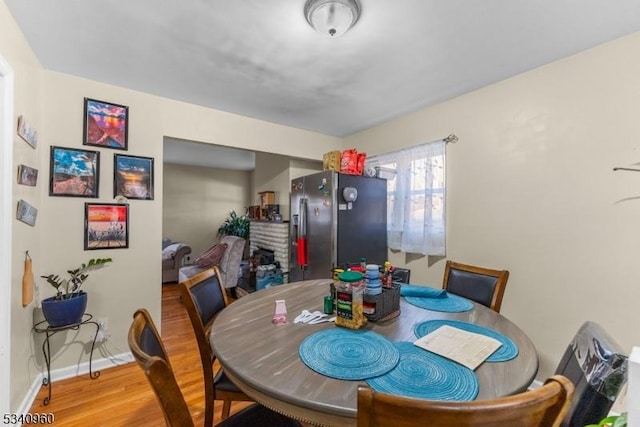 dining area featuring a brick fireplace, baseboards, and wood finished floors