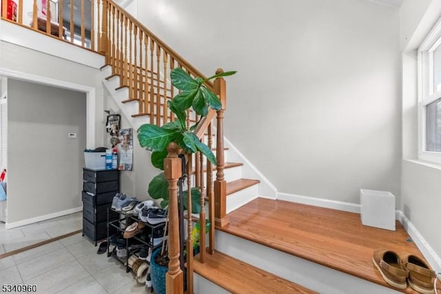 stairway with baseboards and tile patterned floors